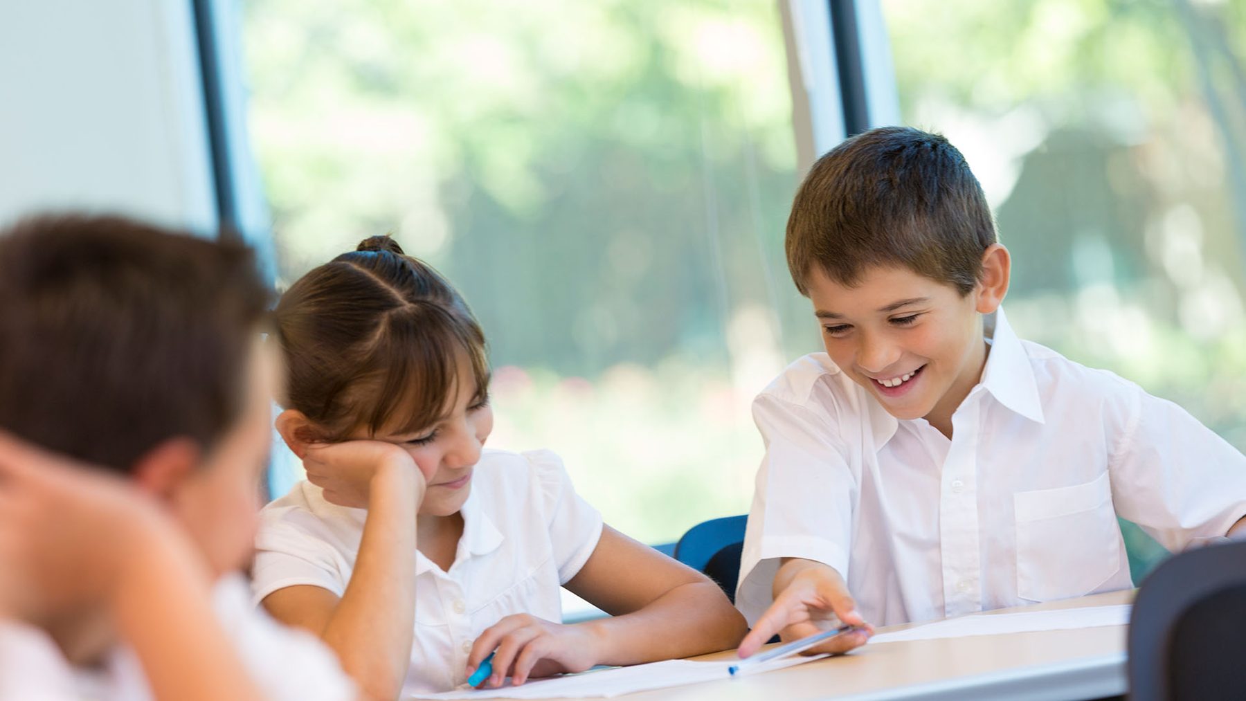 Pupils working together and smiling at a classroom table