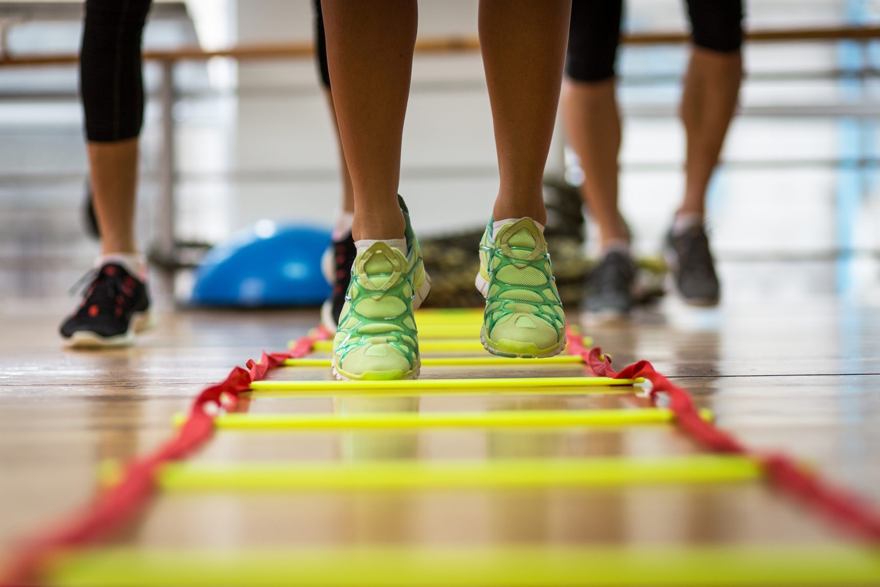 Learners doing footwork drills on an agility ladder in a sports hall